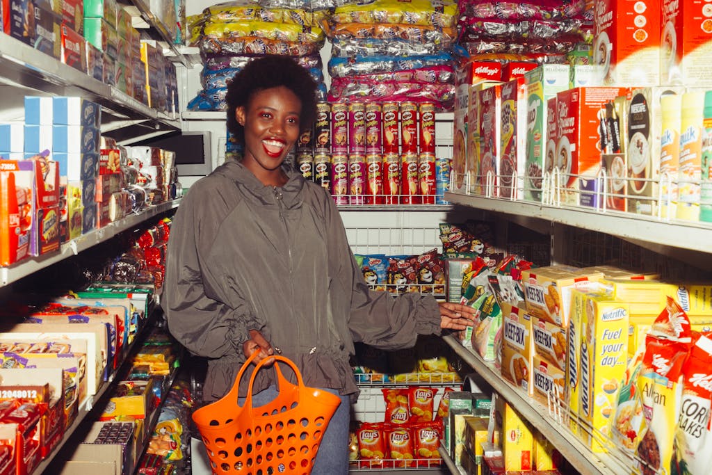 Smiling woman shopping in a grocery aisle filled with colorful products.